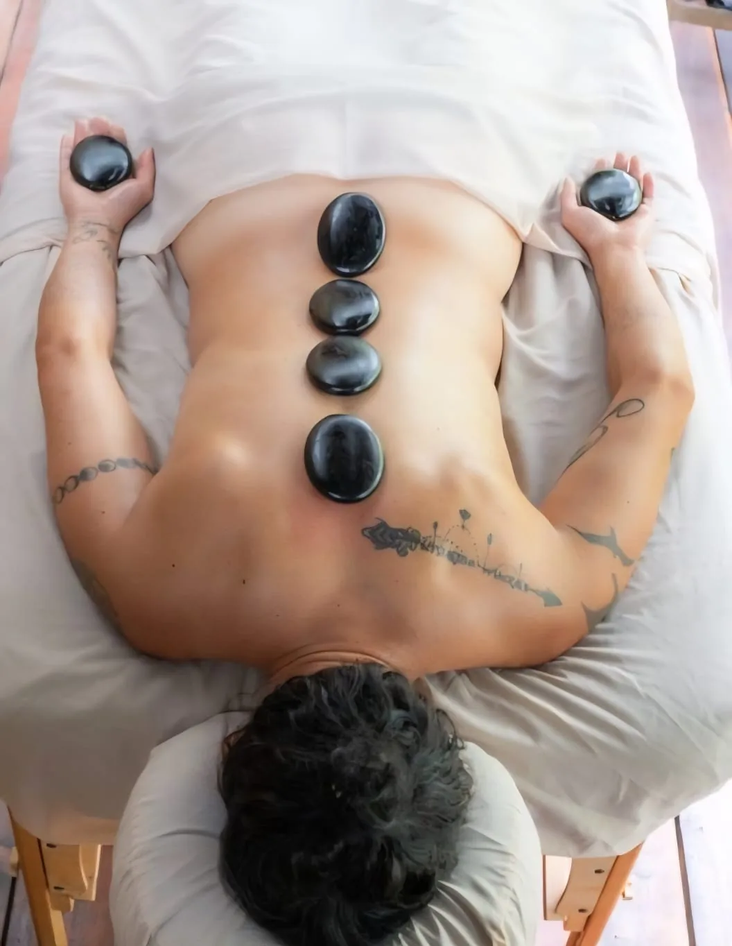 Client receiving a hot stone massage with smooth black basalt stones along the spine